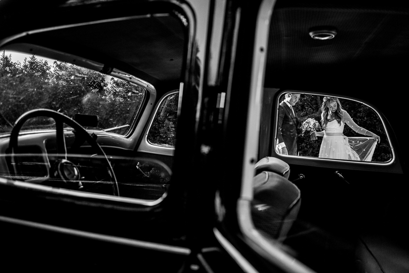Fotografia de boda sesión de pareja de novios a traves del coche de boda en el Pazo el Castriño