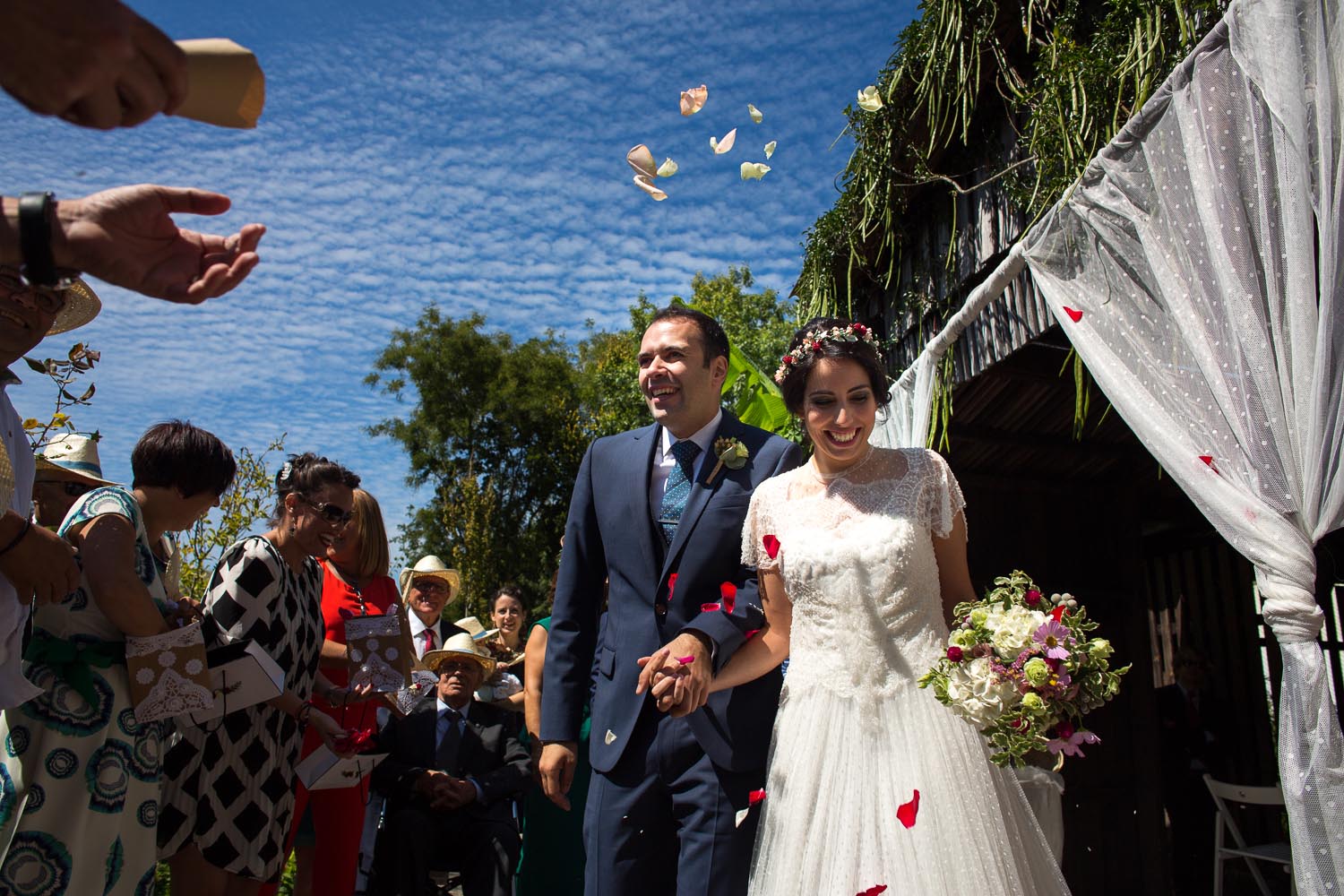Fotografia de boda pareja de novios en la salida de la ceremonia con pétalos