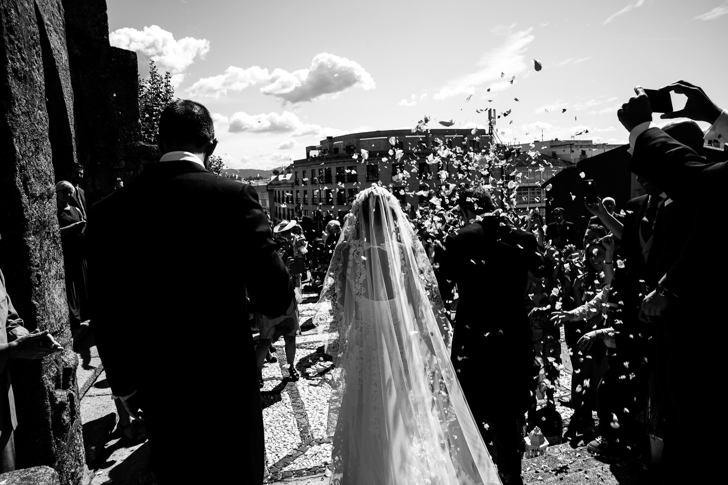 Fotografia de boda pareja de novios en la salida de iglesia con pétalos
